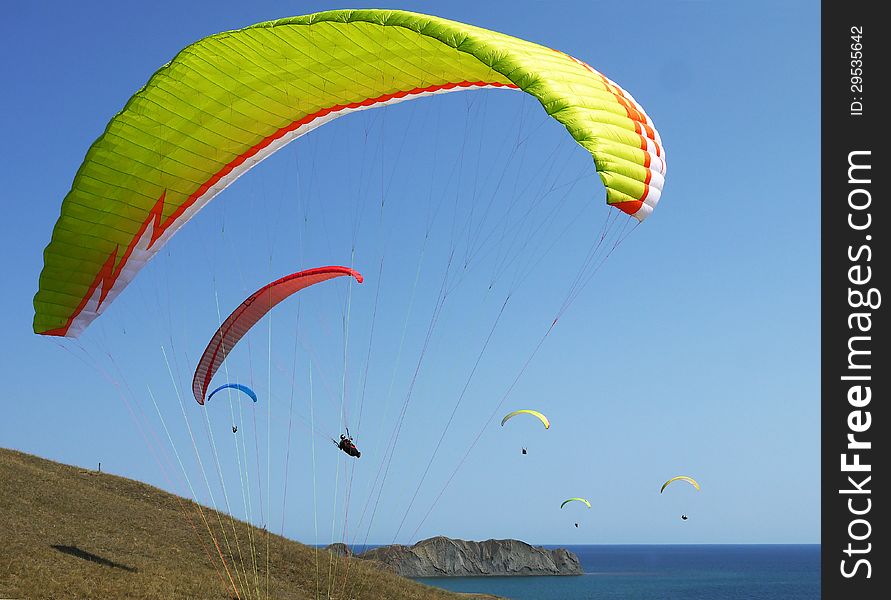 Few paragliders soar over the sea shore