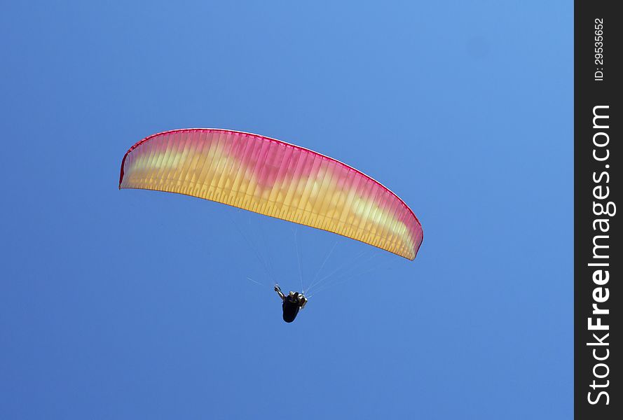 Red and yellow paraglider against the clear blue sky