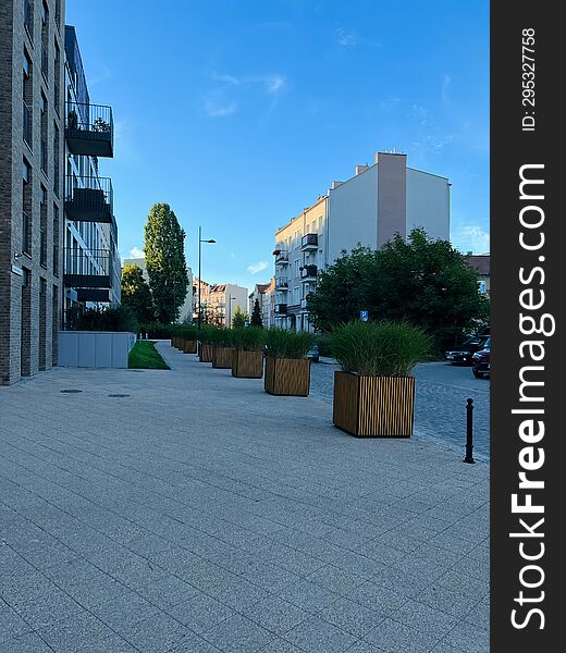 Gdansk, Poland - 08.08.2022: A modern residential area in the city center, a pedestrian zone made of tiles, cubic flowerpots with flowers.