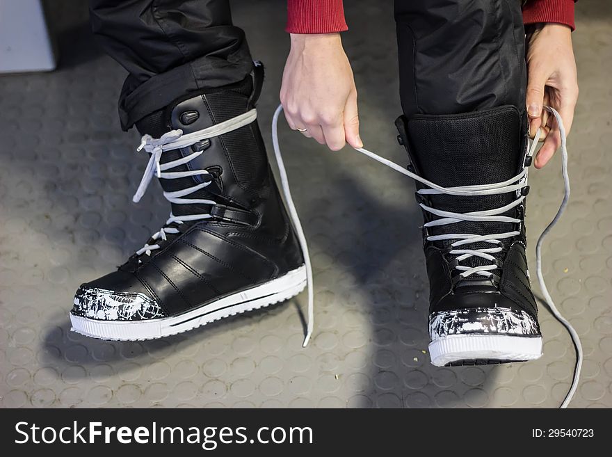 Putting on black snowboard boots and tying shoelaces. Putting on black snowboard boots and tying shoelaces