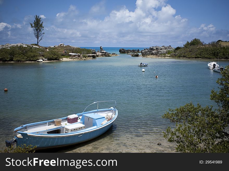 Horizontal photograph of a small blue boat in an ocean cove. Horizontal photograph of a small blue boat in an ocean cove