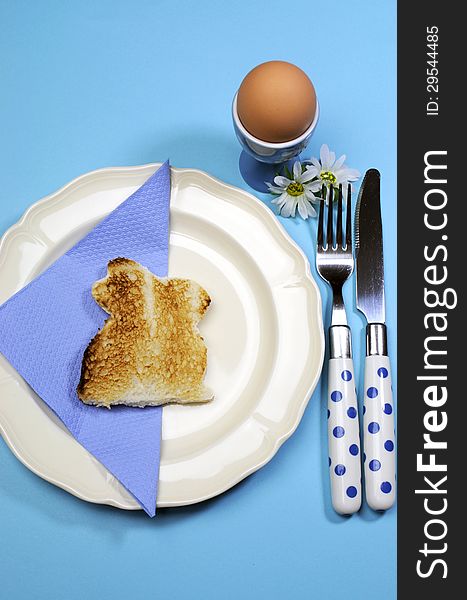 Blue theme Happy Easter breakfast table with bunny rabbit toast and egg. Vertical.