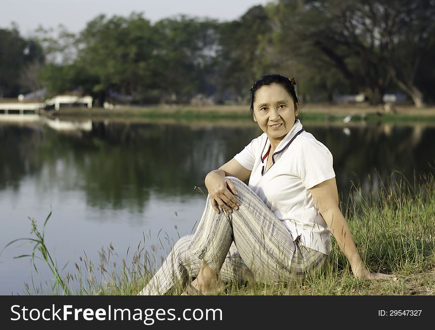 Portrait of smiling woman sitting on background of green field by lake. Portrait of smiling woman sitting on background of green field by lake