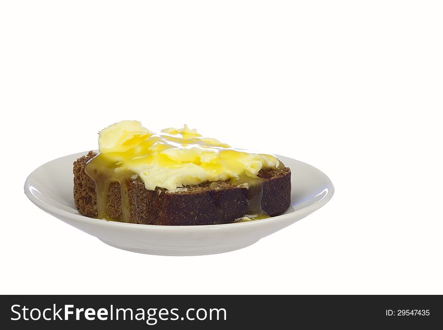 A piece of rye bread with butter and honey on a saucer, isolated on white
