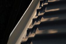 A Dark Blue Roof Next To A White Roof Drain, Illuminated By The Setting Sun During Sunset Royalty Free Stock Images