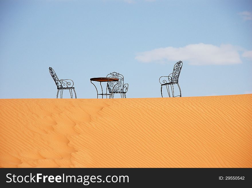 Wrought iron table and chairs on the top of sand dune of Erg Chebbi in the Sahara Desert, Morocco