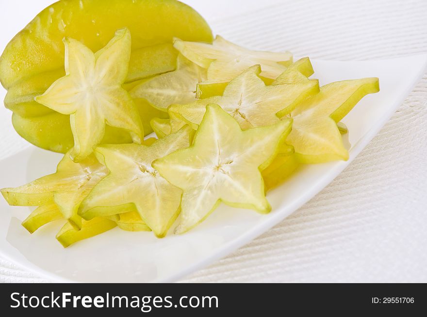 Fresh starfruit and sliced starfruit on white plate. Fresh starfruit and sliced starfruit on white plate