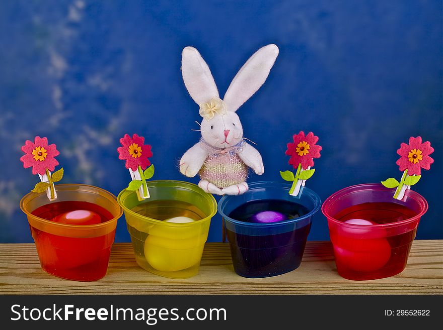 Painted eggs in containers , rabbit and flowers on a blue background. Painted eggs in containers , rabbit and flowers on a blue background.