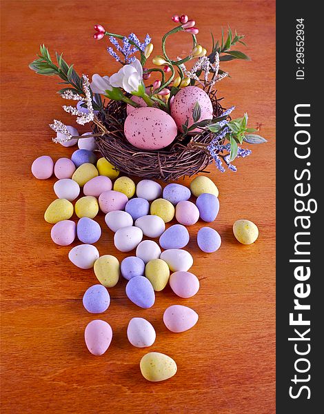 Easter eggs in nest and candies on a wooden background. Easter eggs in nest and candies on a wooden background