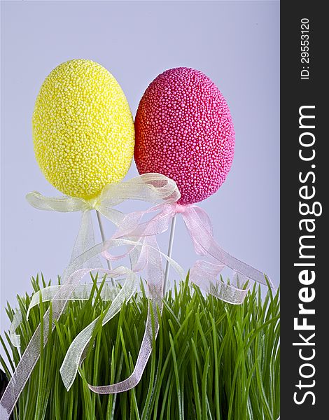 Two Easter decoration eggs in the grass and the white background.