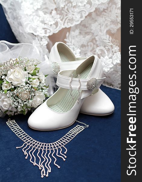 White bridal bouquet, white shoes, necklace and earrings on blue velvet. White bridal bouquet, white shoes, necklace and earrings on blue velvet