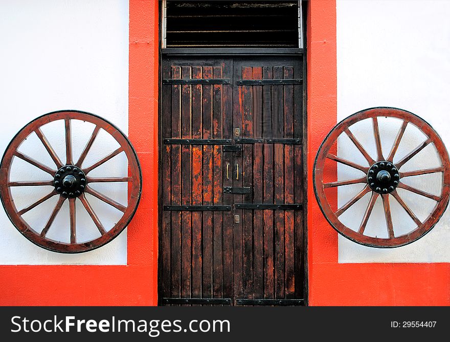 Old wooden door, decorated with two wheels, in Las Palmas de Gran Canaria, Spain. Old wooden door, decorated with two wheels, in Las Palmas de Gran Canaria, Spain.