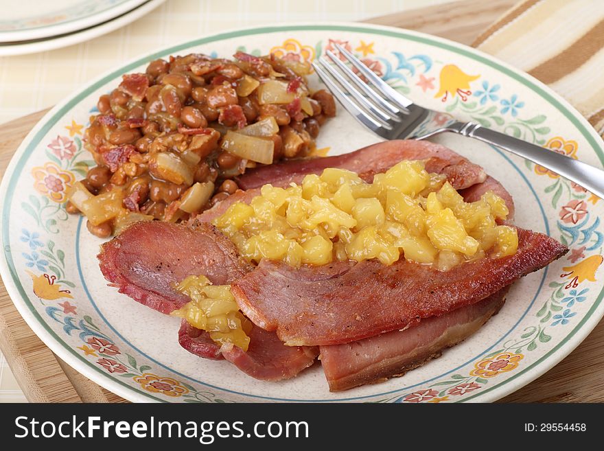 Ham with pineapple sauce and baked beans on a plate. Ham with pineapple sauce and baked beans on a plate