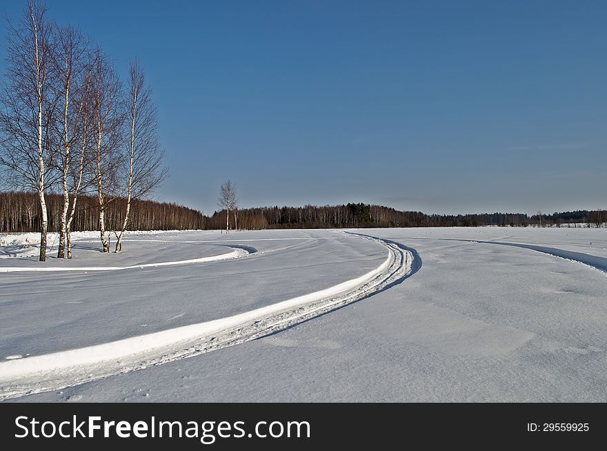 Snow-covered field with snowmobile tracks, winter sunny day. Snow-covered field with snowmobile tracks, winter sunny day