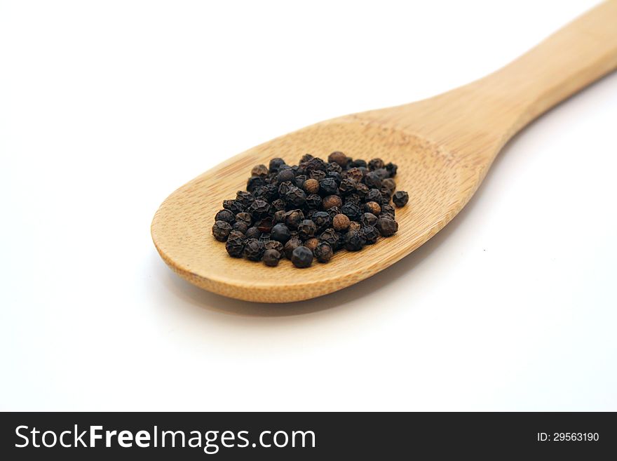 Pepper in wooden spoon over white background