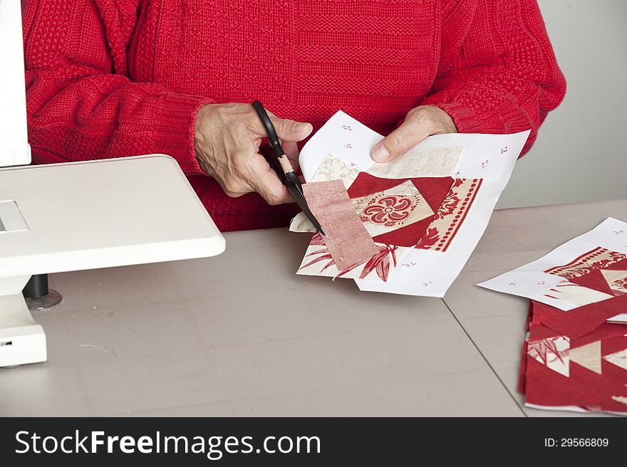 A quilter cuts off excess material for accurate seam allowance of a quilt block. A quilter cuts off excess material for accurate seam allowance of a quilt block.