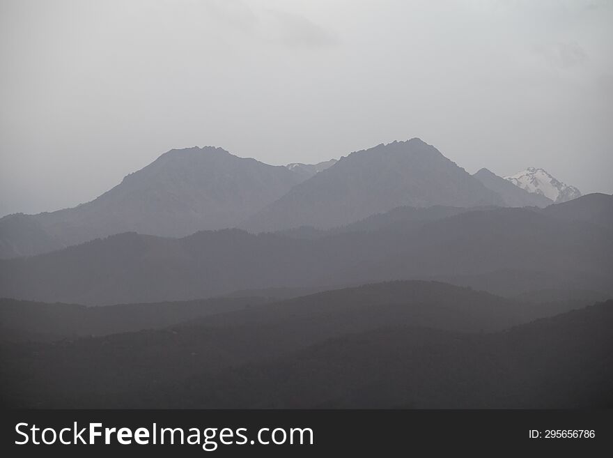 Landscape of the Trans-Ili Alatau mountains on an early cloudy morning in the morning fog