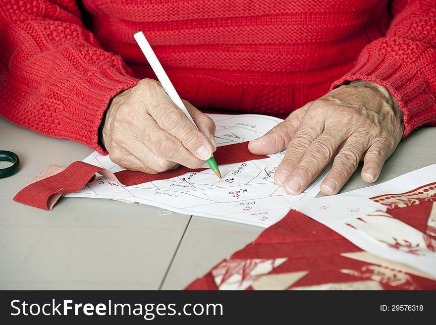 A quilter marks a paper pieced foundation for numerical assembly. A quilter marks a paper pieced foundation for numerical assembly.