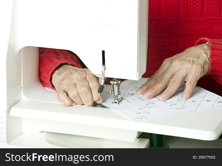 A quilter sews foundation paper piecing to a section of fabric. A quilter sews foundation paper piecing to a section of fabric.