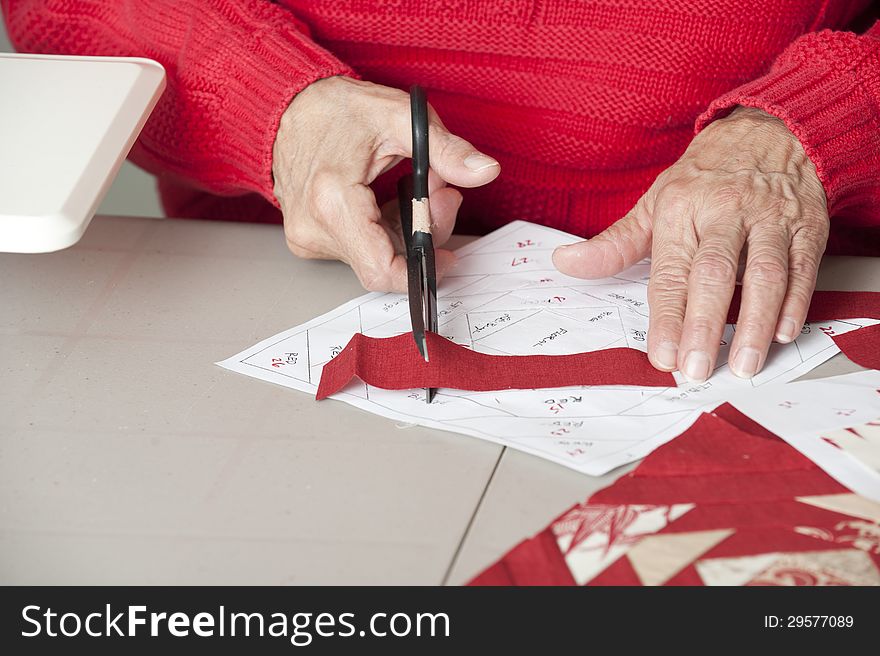 A quilter cuts red fabric to fit foundation paper piecing. A quilter cuts red fabric to fit foundation paper piecing.