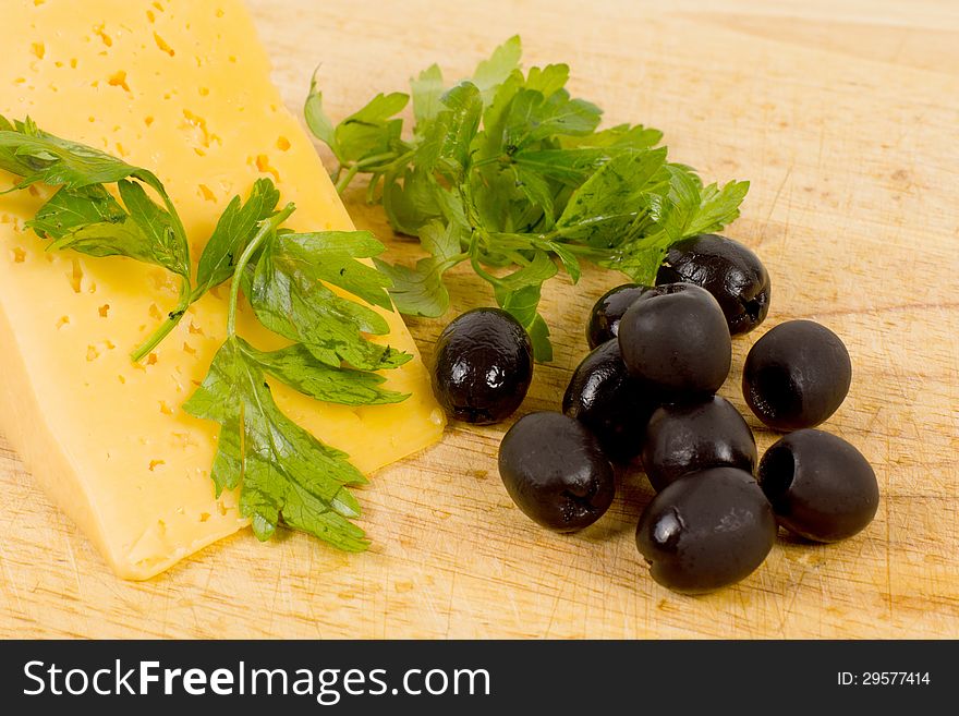 Close up shot of black olives and piece of cheese on wooden kitchen table. Close up shot of black olives and piece of cheese on wooden kitchen table