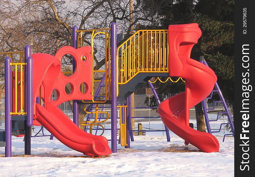 Two bright red slides of a childrenâ€™s playground equipment outdoors in winter. Two bright red slides of a childrenâ€™s playground equipment outdoors in winter.