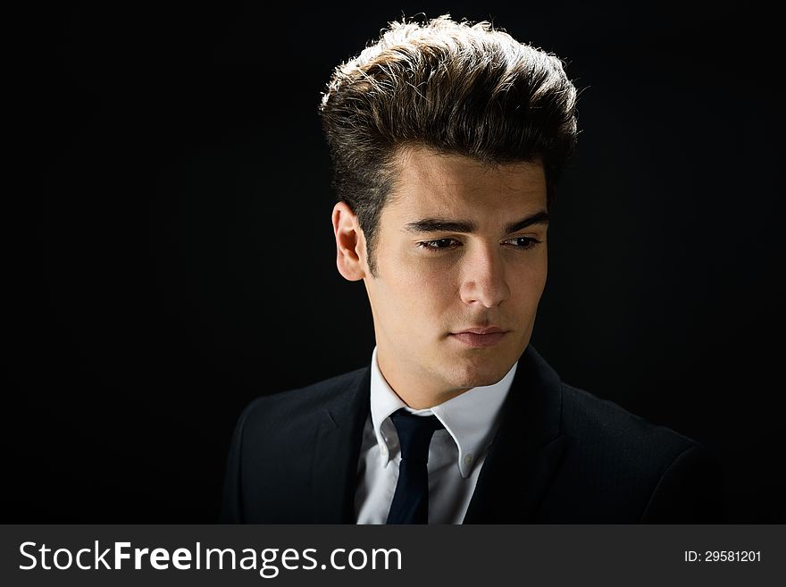 Portrait of a young businessman, on black background