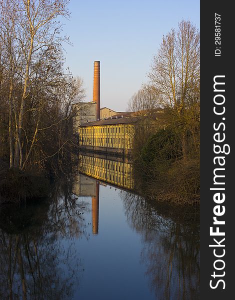 An old factory near a river, with beautiful reflection. An old factory near a river, with beautiful reflection