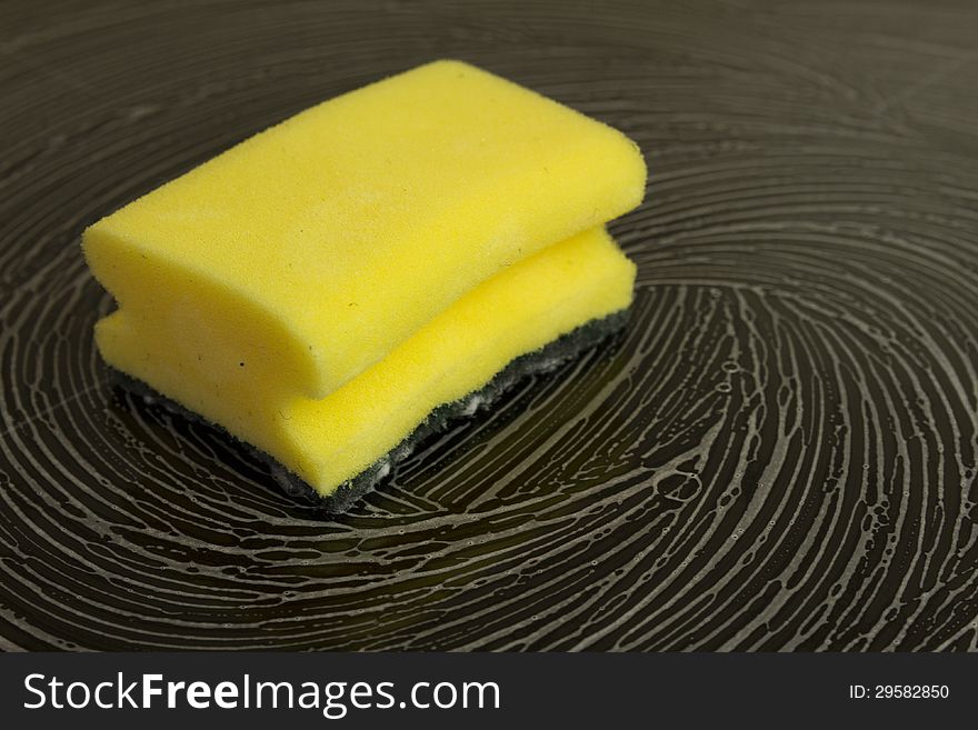 Cleaning sponge with white foam laying on black glassy stove