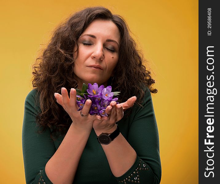 Curly Woman Smelling Crocus Flowers With Close Eyes