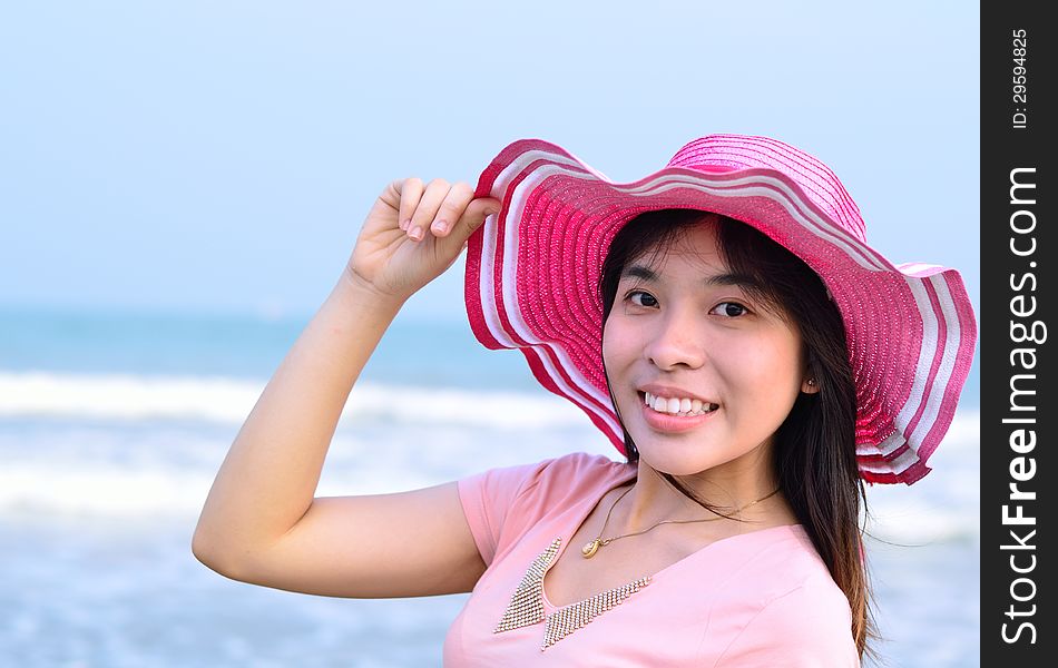 Beautiful asian woman relaxation on beach with hat and pink decoration