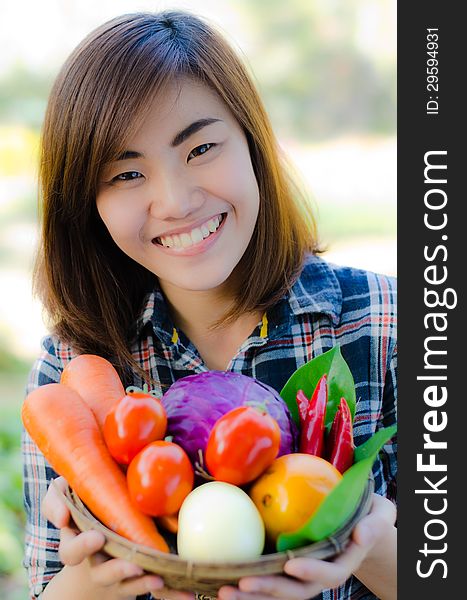 Beautifull asian woman holding fresh vegetable bucket