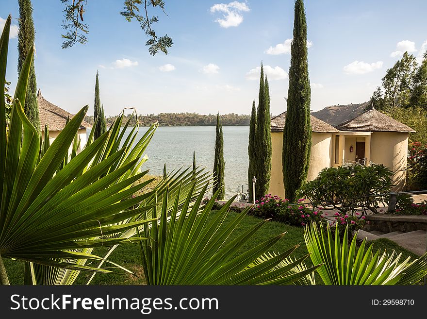 Cottages in a beautiful setting with palm leaves, well maintained garden and a lake in the background. Cottages in a beautiful setting with palm leaves, well maintained garden and a lake in the background