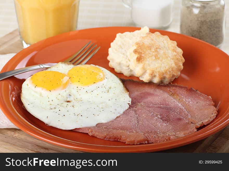 Ham with fried eggs and a biscuit on a plate. Ham with fried eggs and a biscuit on a plate