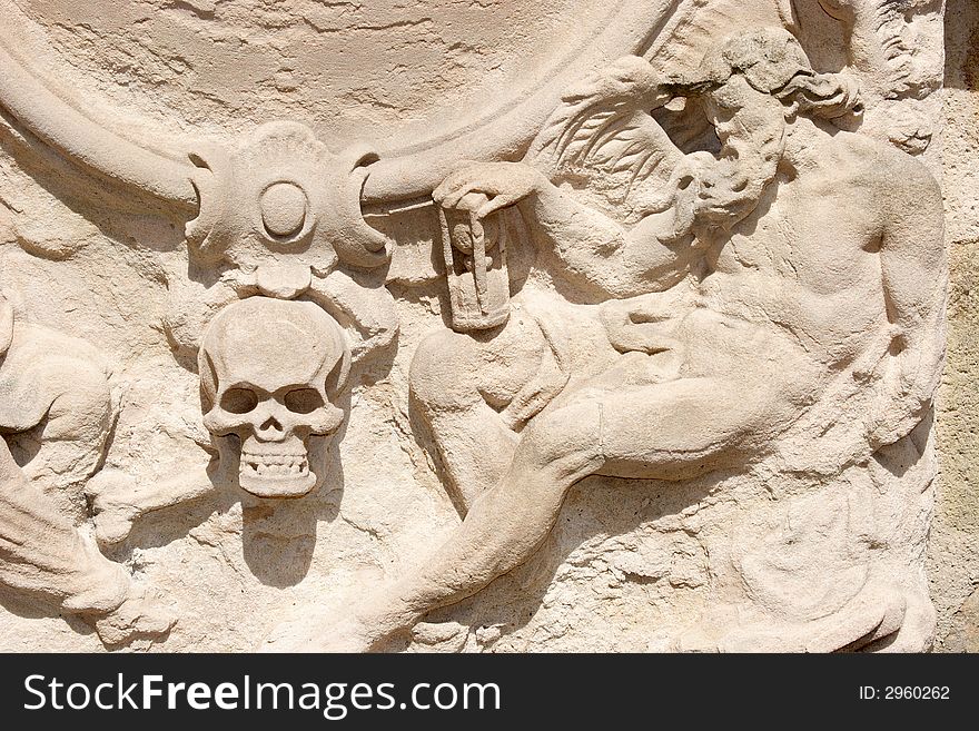 Bas-relief with a skull and person holding a hourglass. Bas-relief with a skull and person holding a hourglass