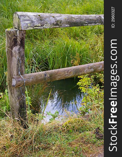 Close up of a wooden fence along a marsh (with reflection in water). Close up of a wooden fence along a marsh (with reflection in water).