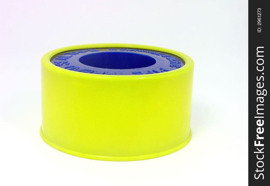 Photo showing close view of yellow sticky tape case and blue reel over white background isolated