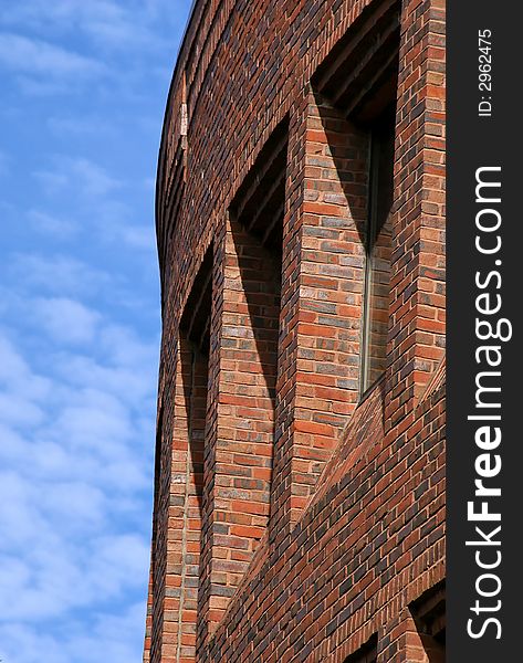 Majestic yet simple curved brick building  against a light blue sky with soft clouds located in harvard square, cambridge massachusetts