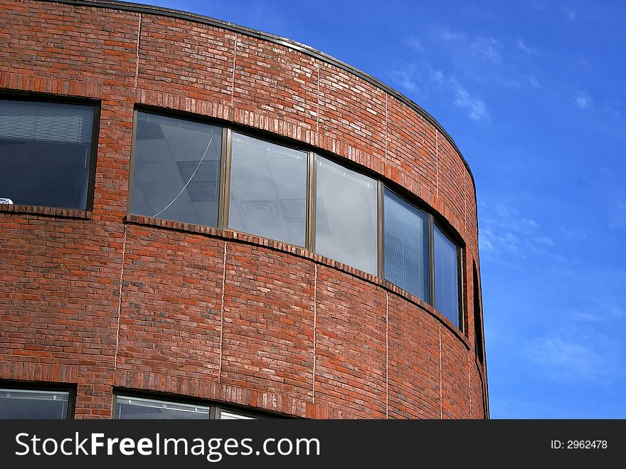 Majestic yet simple curved brick building  against a light blue sky with soft clouds located in harvard square, cambridge massachusetts. Majestic yet simple curved brick building  against a light blue sky with soft clouds located in harvard square, cambridge massachusetts