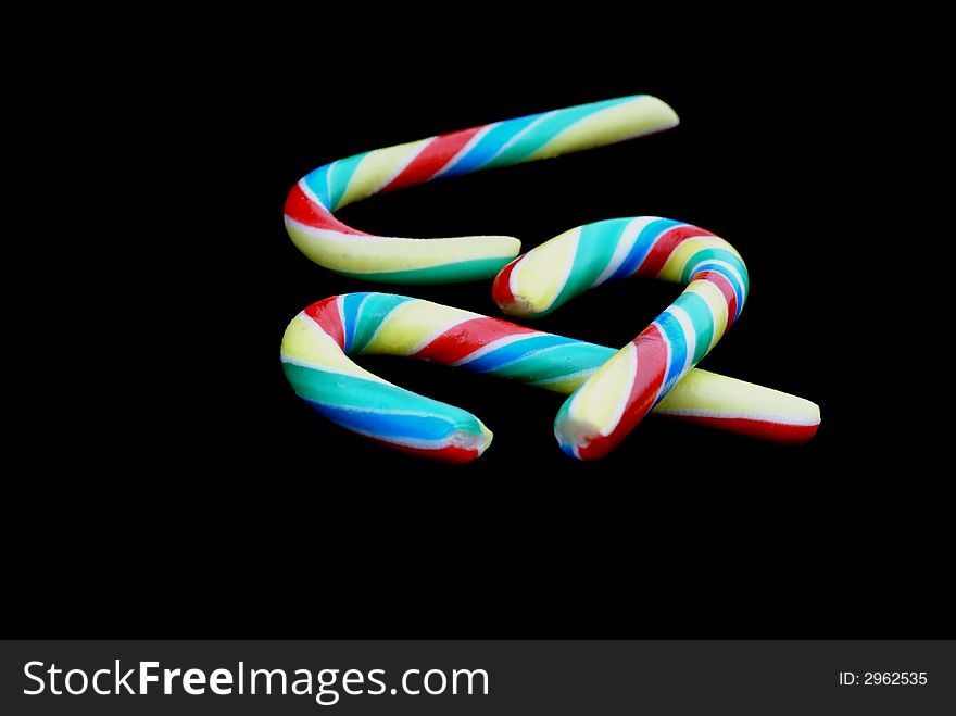Three striped candy canes in front of black background. Three striped candy canes in front of black background.