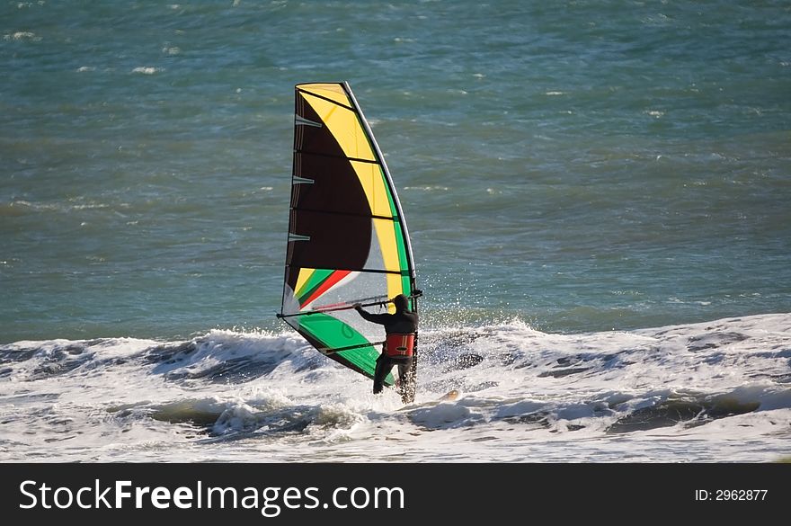 Windsurfer sailing along in the surf