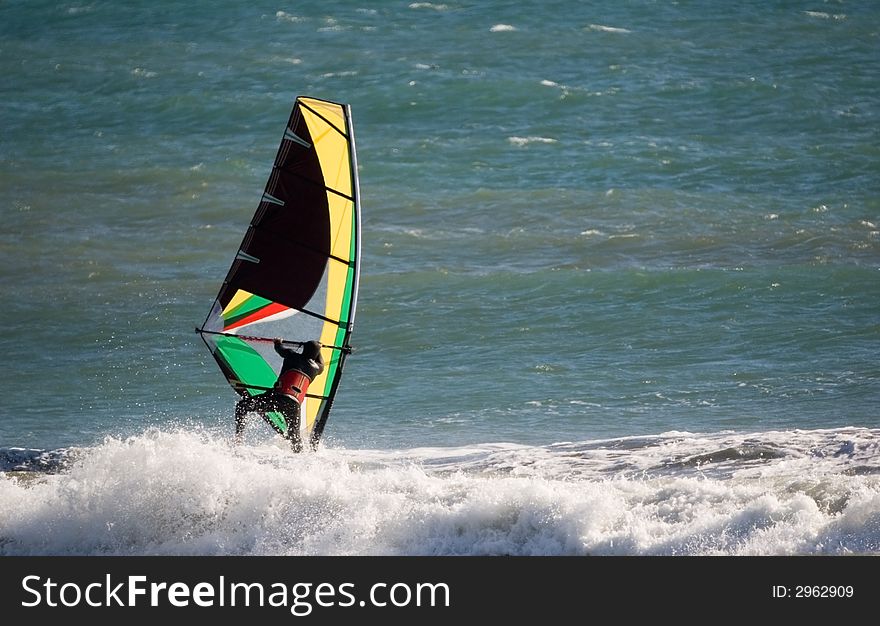 Windsurfer sailing along in the surf