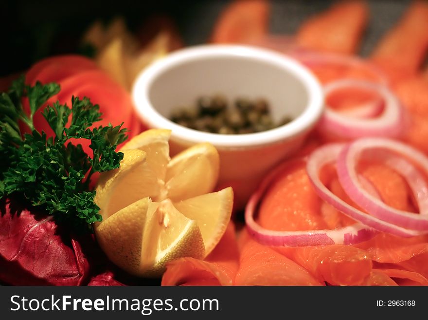 A smoked salmon platter with onions, lemon, and capers. A smoked salmon platter with onions, lemon, and capers