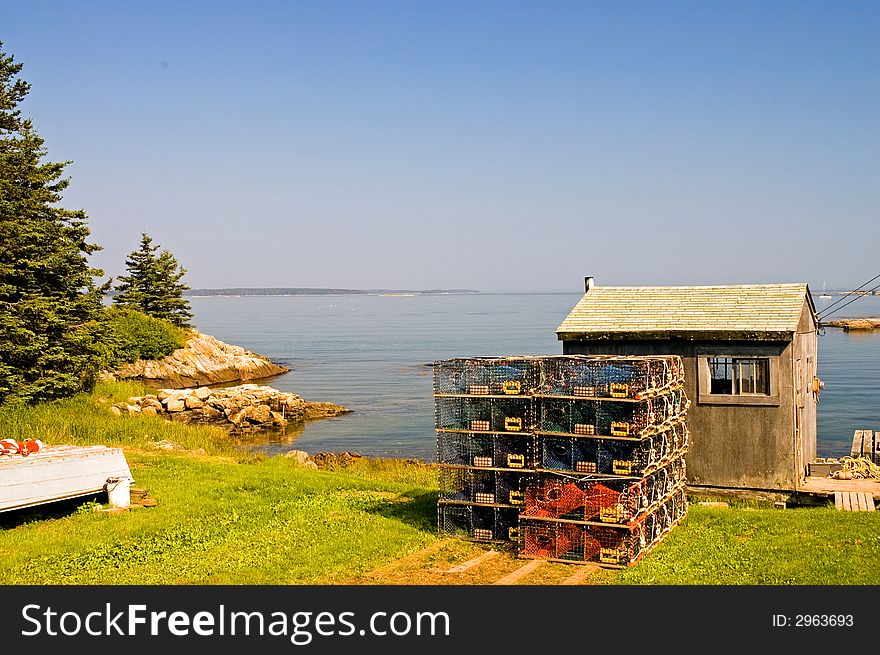 A view of a small fishing shack on a small saltwater cove with a pile of lobster traps behind it on Swans Island, Maine. A view of a small fishing shack on a small saltwater cove with a pile of lobster traps behind it on Swans Island, Maine.