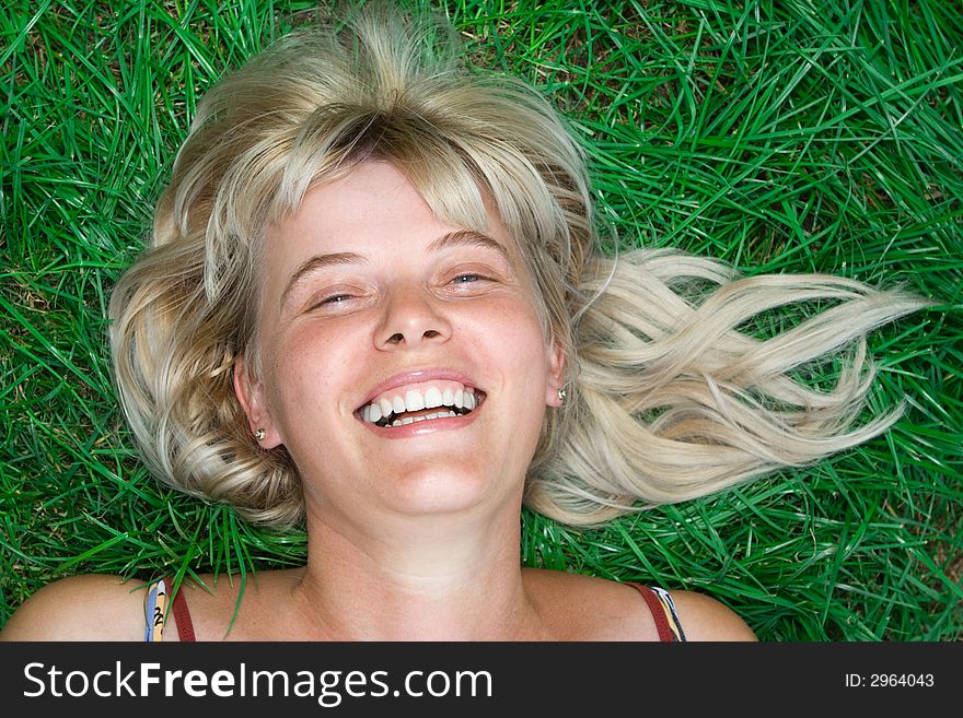 Beauty blonde happy woman lie on green grass