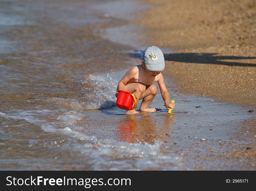 Small Kid play with buckets and shovel on the beach. Small Kid play with buckets and shovel on the beach