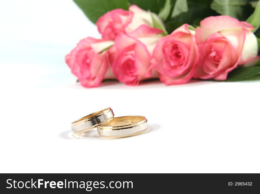 Wedding rings and roses on white background