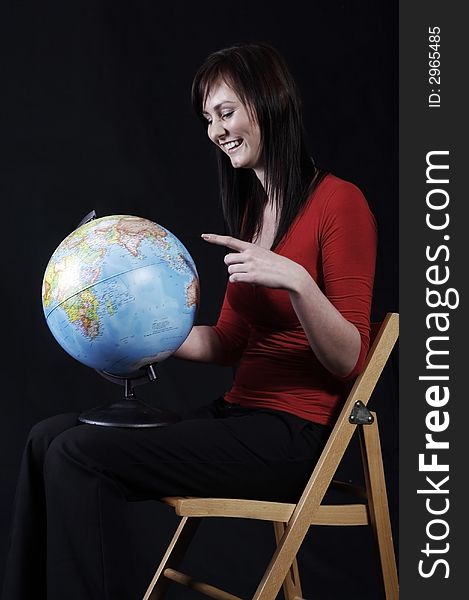 Pretty girl pointing at the globe, black background. Pretty girl pointing at the globe, black background