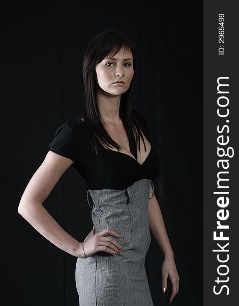 Elegant girl in black and grey top, black background. Elegant girl in black and grey top, black background