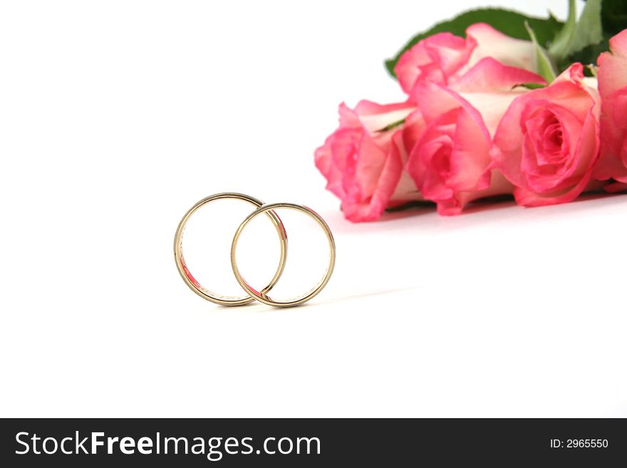 Wedding rings and roses on white background